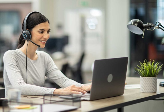 Woman at a desk with a computer and a headset on